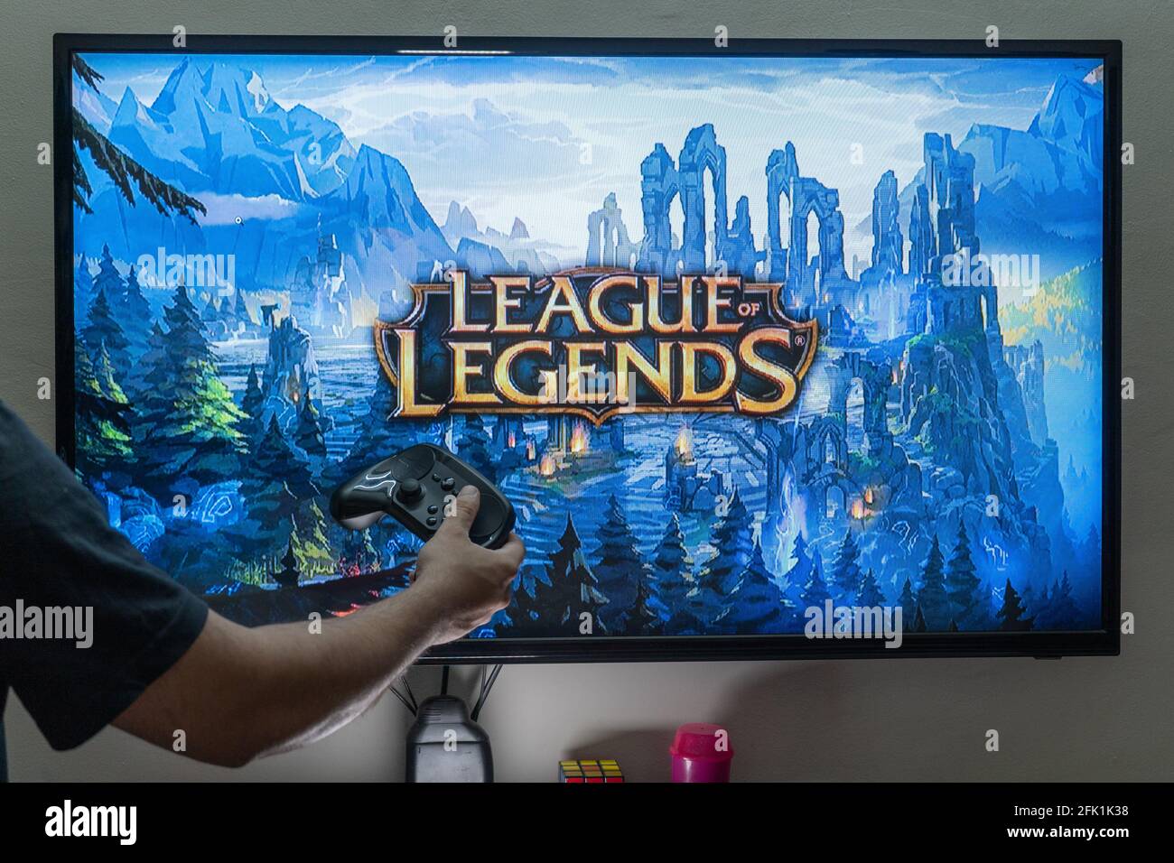 Uomo che tiene il controller di vapore davanti a uno schermo di caricamento Il popolare RPG MMORPG campionato di leggende molto amato gioco popolare con milioni di online Foto Stock