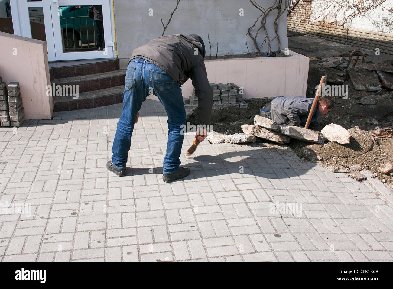 Dnepropetrovsk, Ucraina - 03.26.2021: Un lavoratore spazza su sporcizia dopo la sostituzione dei tubi fognari. Foto Stock