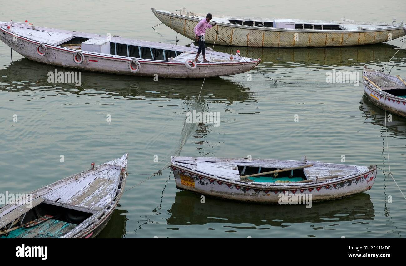 Varanasi, India - 2021 aprile: Un uomo che prepara la sua barca su un ghat sul fiume Ganga a Varanasi il 5 aprile 2021 a Uttar Pradesh, India. Foto Stock