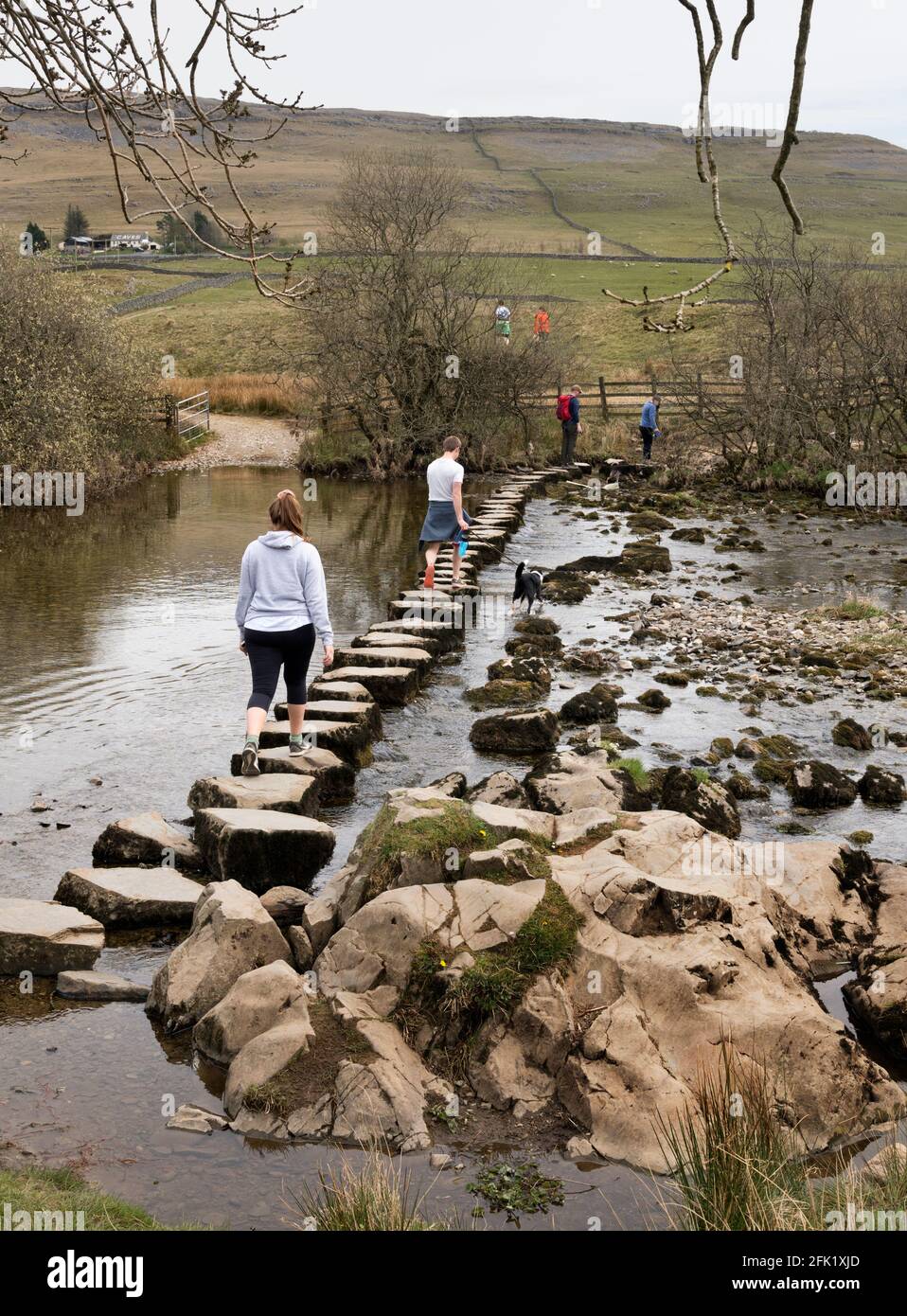 Gli escursionisti attraversano le pietre passo attraverso il fiume Doe, Ingleton, Yorkshire Dales National Park, Regno Unito Foto Stock