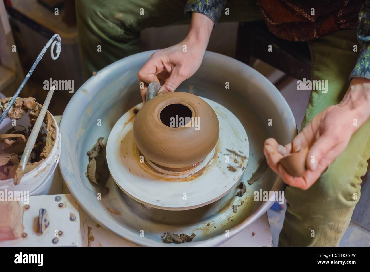 Professional potter pot di sagomatura con un attrezzo speciale nel laboratorio di ceramica Foto Stock