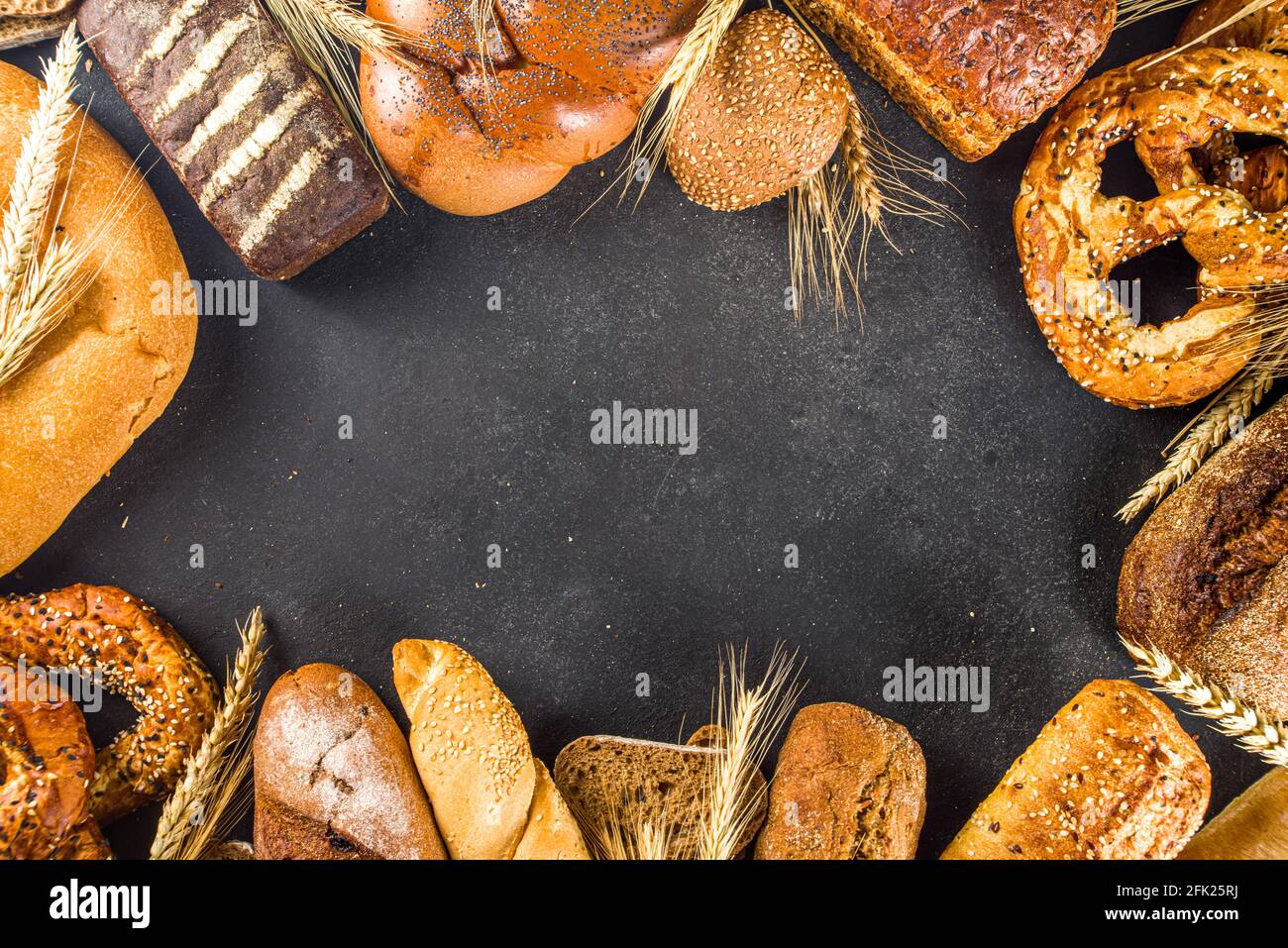Assortimento di vari deliziosi pane appena sfornato, su fondo nero cemento vista dall'alto spazio copia Foto Stock