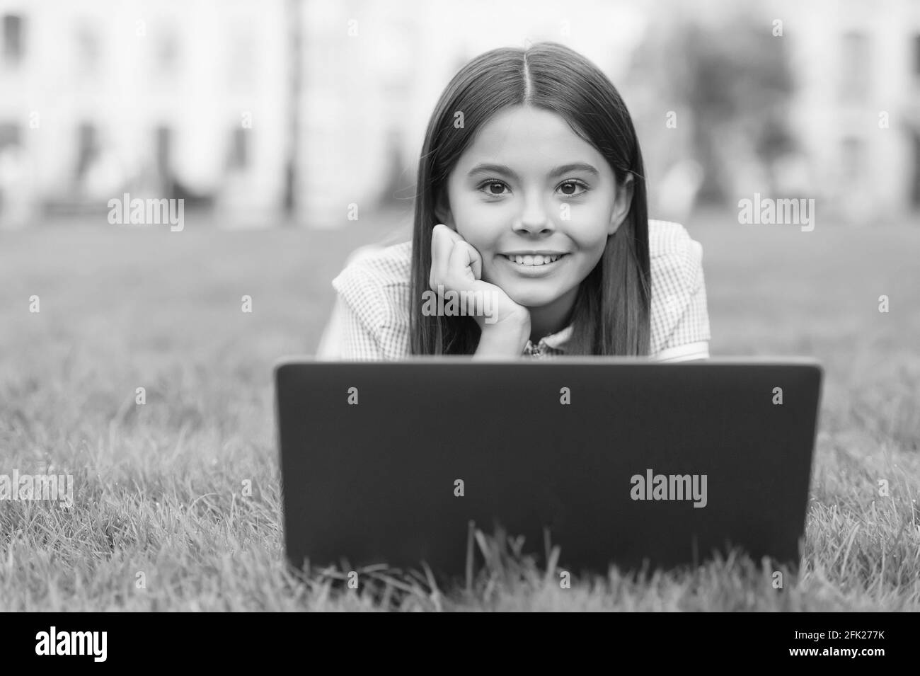 felice capretto che lavora sul laptop. formazione in linea. ritorno alla scuola. ragazza teen usa il calcolatore sull'erba verde nel parco. bambino con il notebook. nuova tecnologia dentro Foto Stock