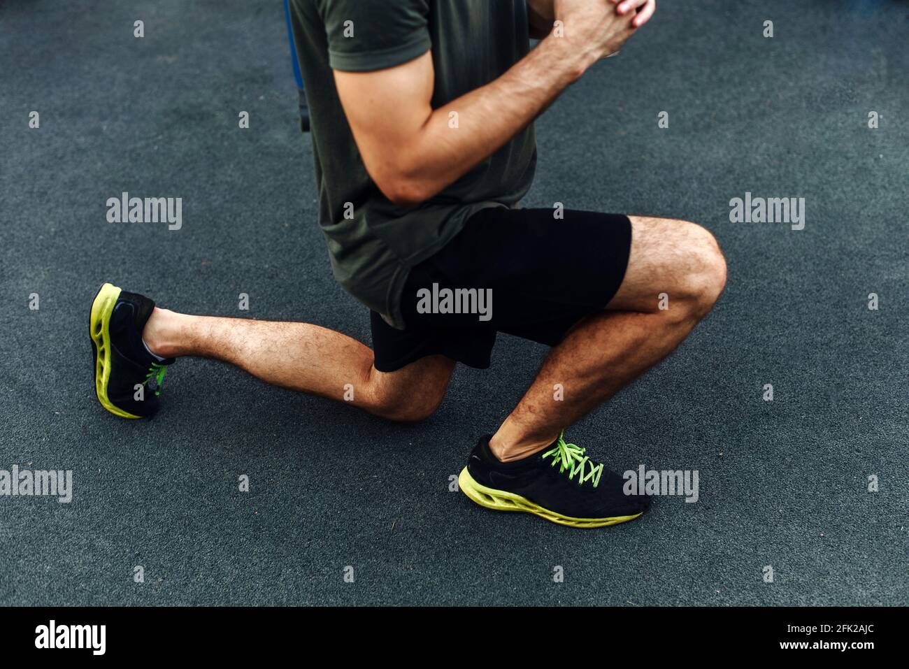 Atleta giovane e sano che fa squat sul parco giochi per strada. Giovane uomo che si esercita all'esterno. Primo piano. Foto Stock