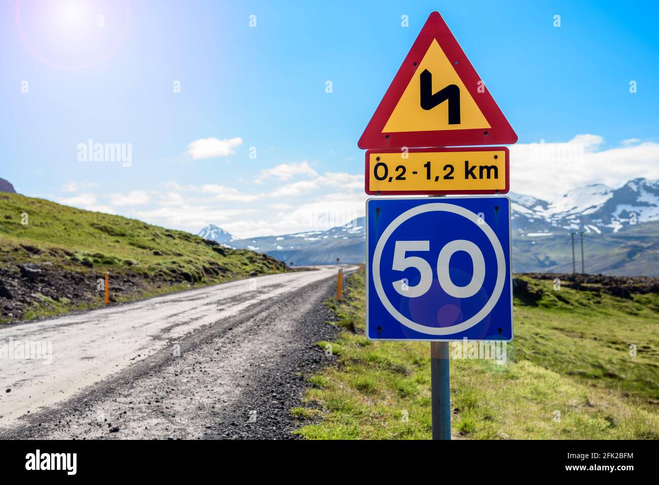 Segnale di avvertenza stradale triangolare con limite di velocità lungo una remota strada di montagna ghiaia in una giornata estiva soleggiata Foto Stock