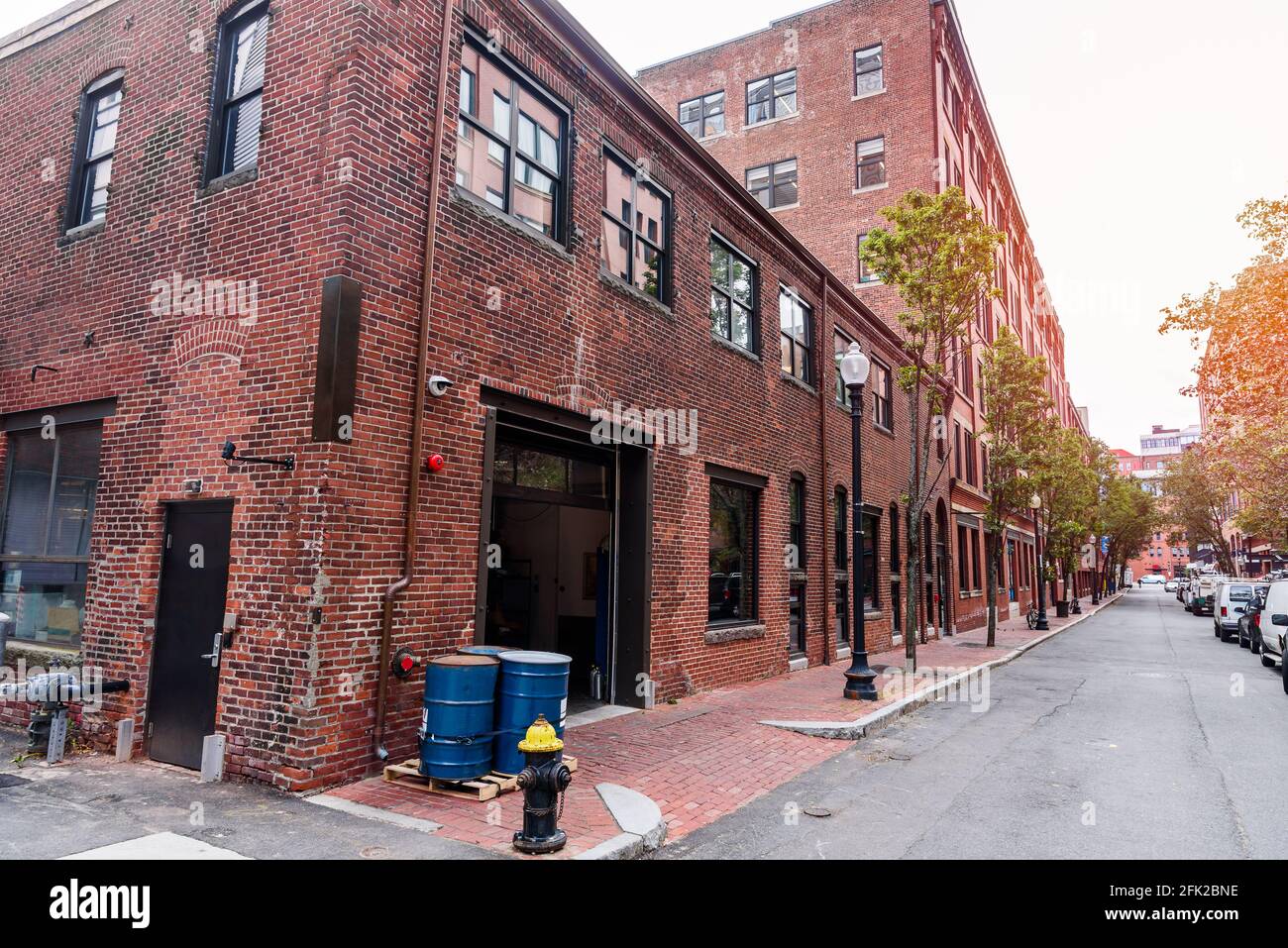 Edifici ristrutturati in mattoni rossi lungo una stretta strada alberata autunno Foto Stock