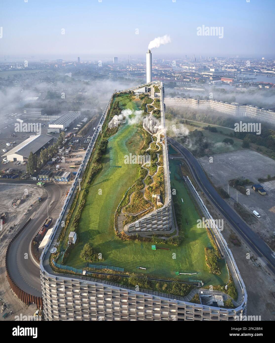 Vista a distanza con nuvole e pendenza del tetto verde. Centrale elettrica di CoppenHill, Copenhagen, Danimarca. Architetto: BIG Bjarke Ingels Group, 2019. Foto Stock