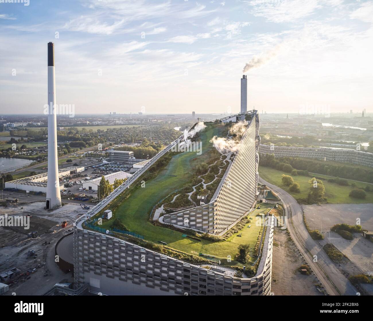 Vista a distanza con nuvole e pendenza del tetto verde. Centrale elettrica di CoppenHill, Copenhagen, Danimarca. Architetto: BIG Bjarke Ingels Group, 2019. Foto Stock