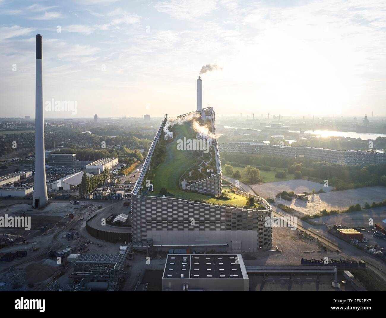 Vista a distanza con nuvole e pendenza del tetto verde. Centrale elettrica di CoppenHill, Copenhagen, Danimarca. Architetto: BIG Bjarke Ingels Group, 2019. Foto Stock