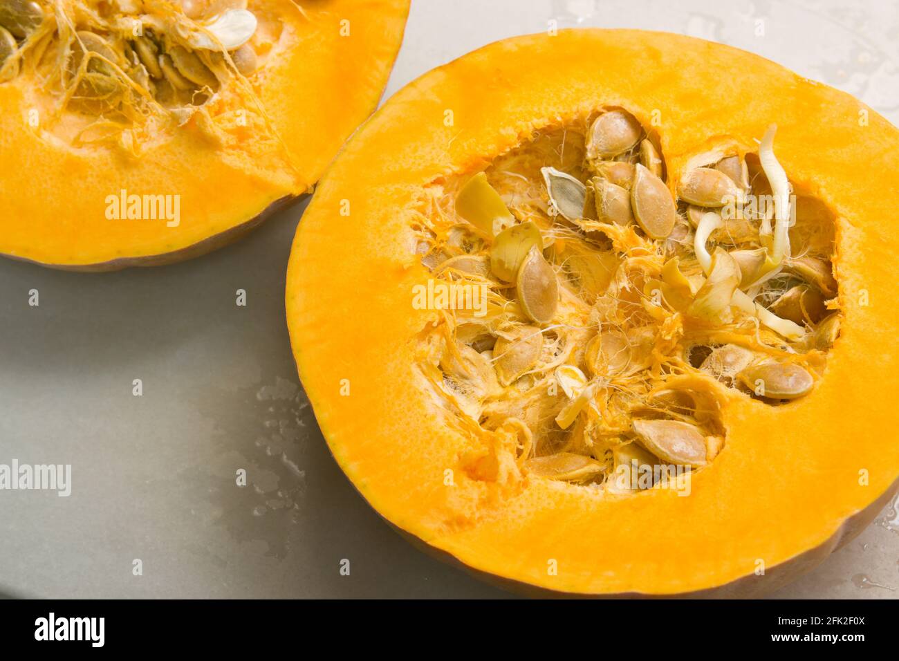 Primo piano di una zucca aperta a metà in cui alcuni dei suoi semi hanno germogliato Foto Stock