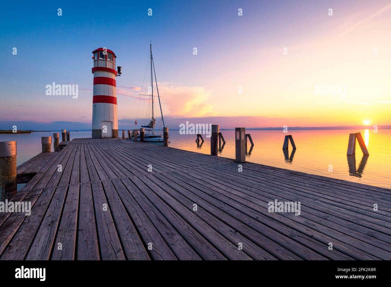 Faro di lago di Neusiedl, Podersdorf am See, Burgenland, Austria. Faro al tramonto in Austria. Il molo di legno con il faro in Podersdorf sul lak Foto Stock