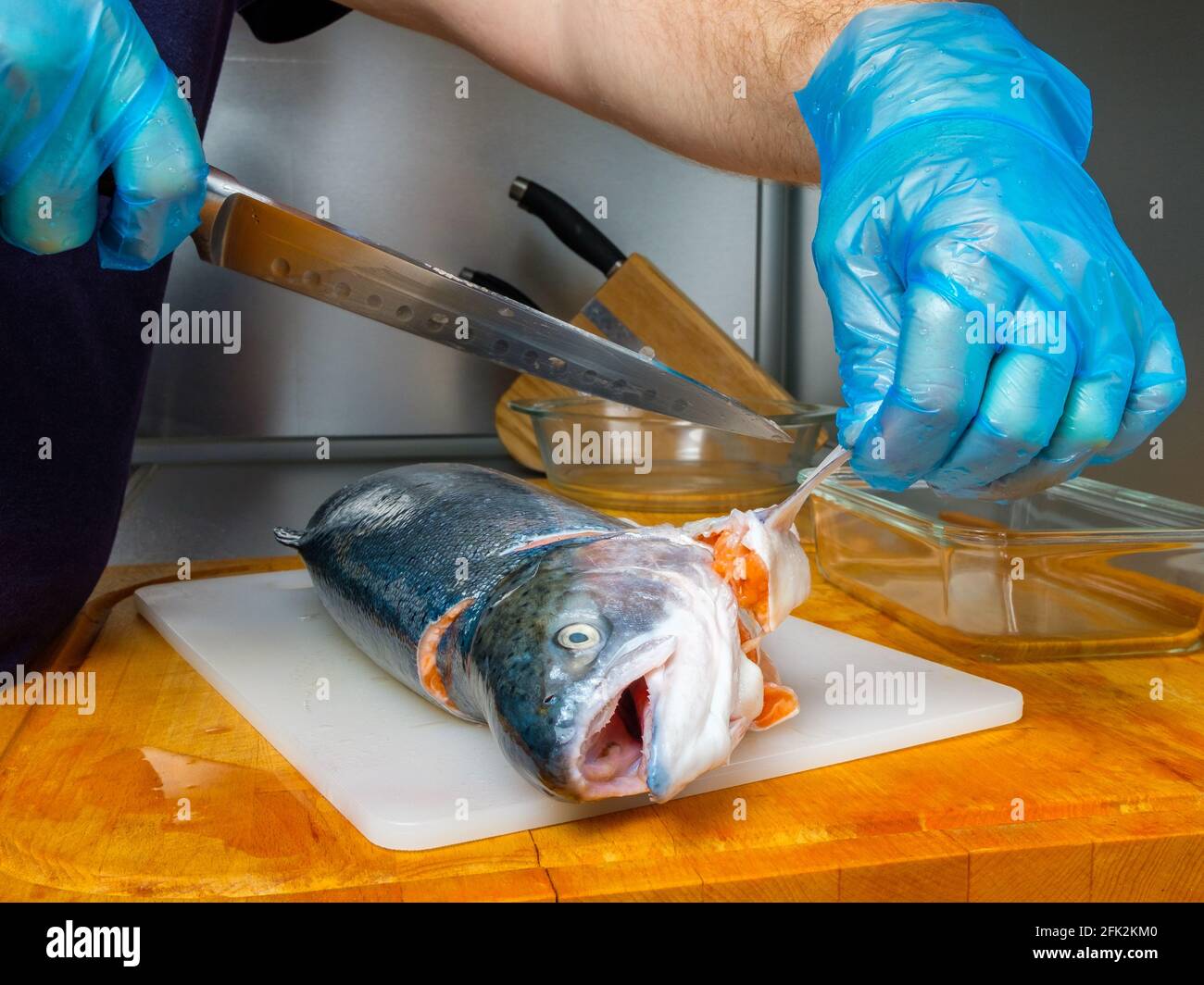 Le lancette del cuoco tagliate le pinne sulla carcassa del salmone con un  coltello. Tagliare pesce fresco in cucina su un tagliere Foto stock - Alamy