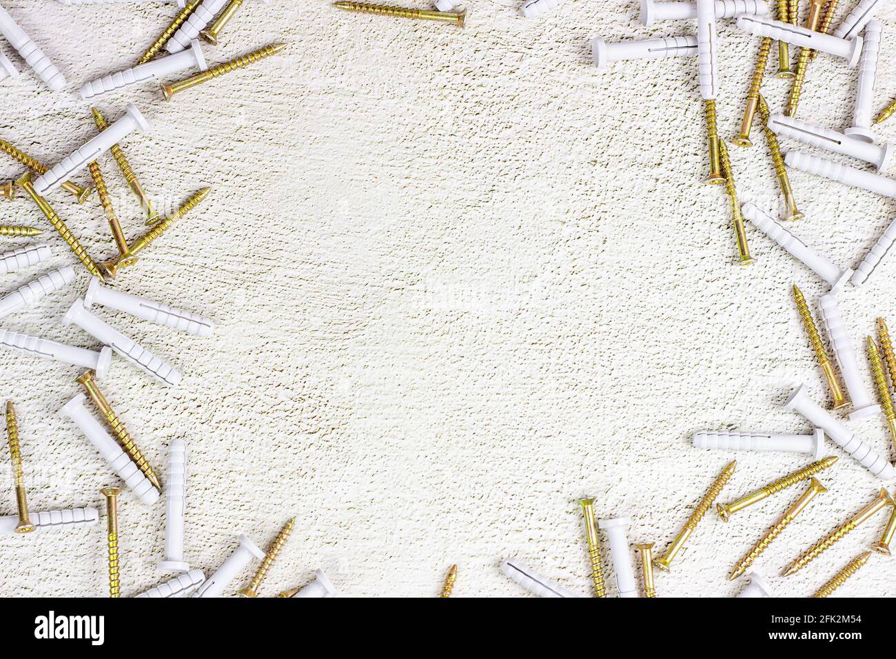 Molti tasselli in acciaio e plastica per la riparazione del telaio su fondo in cemento grigio chiaro con spazio di copia. Fai da te, miglioramento della casa e concetto di costruzione della casa. Foto Stock