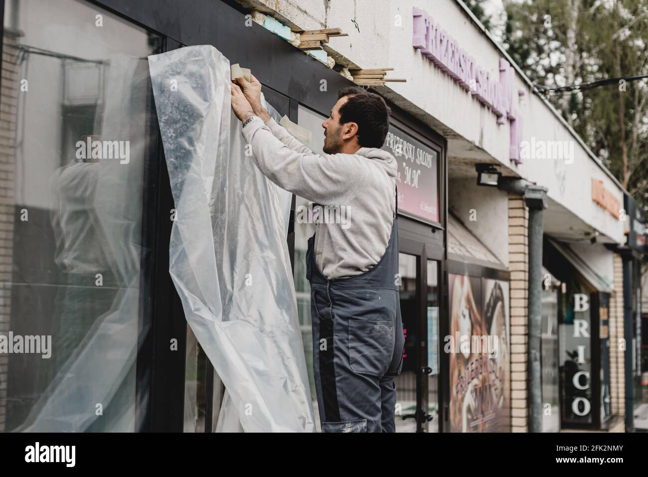 Sarajevo, Bosnia-Erzegovina - 26.04.2021: Riapertura del negozio, lavoratore rinnovando il fronte del negozio dopo il covid 19 blocco Foto Stock