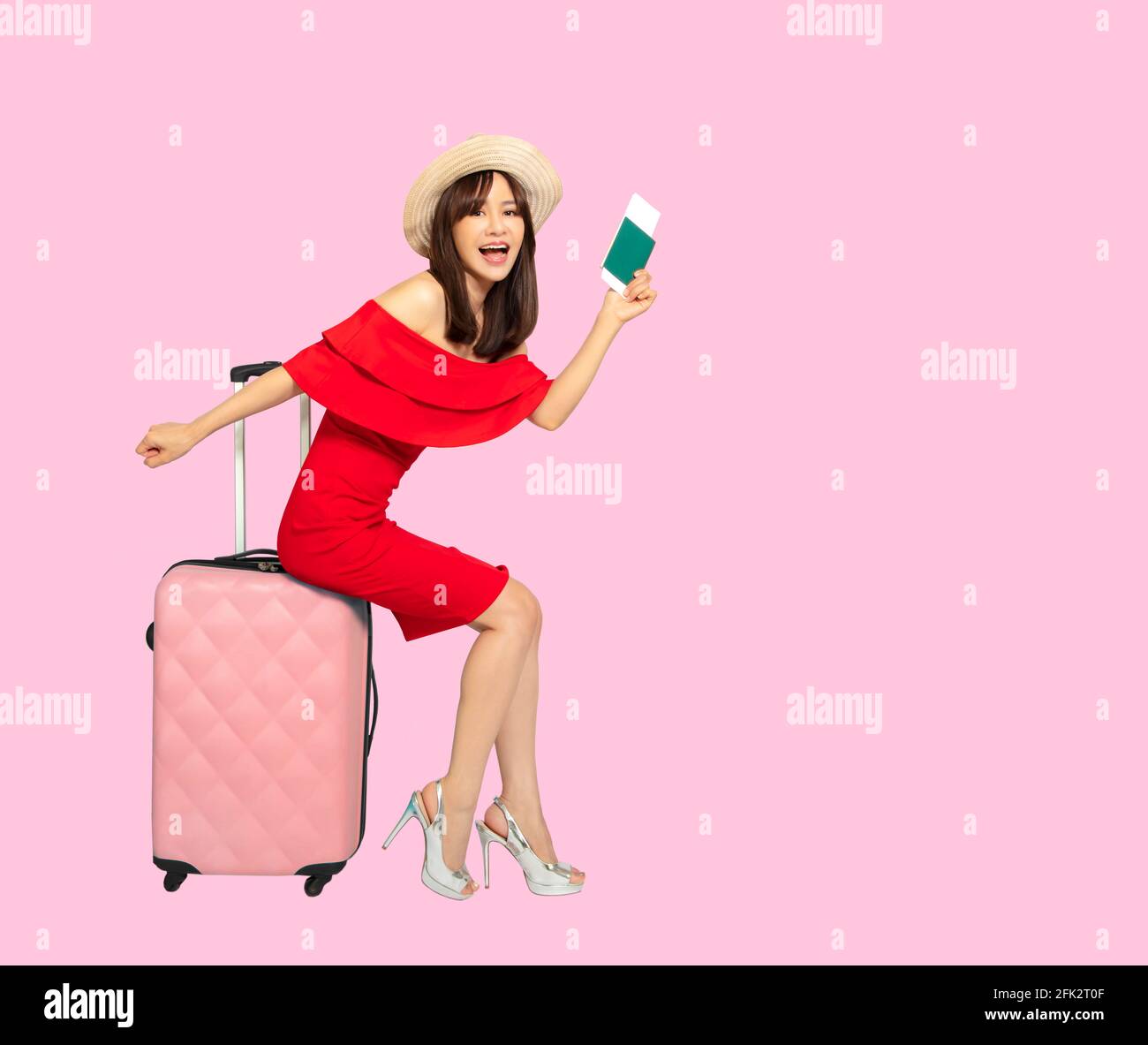Felice giovane donna viaggiatore con valigia su sfondo rosa Foto Stock