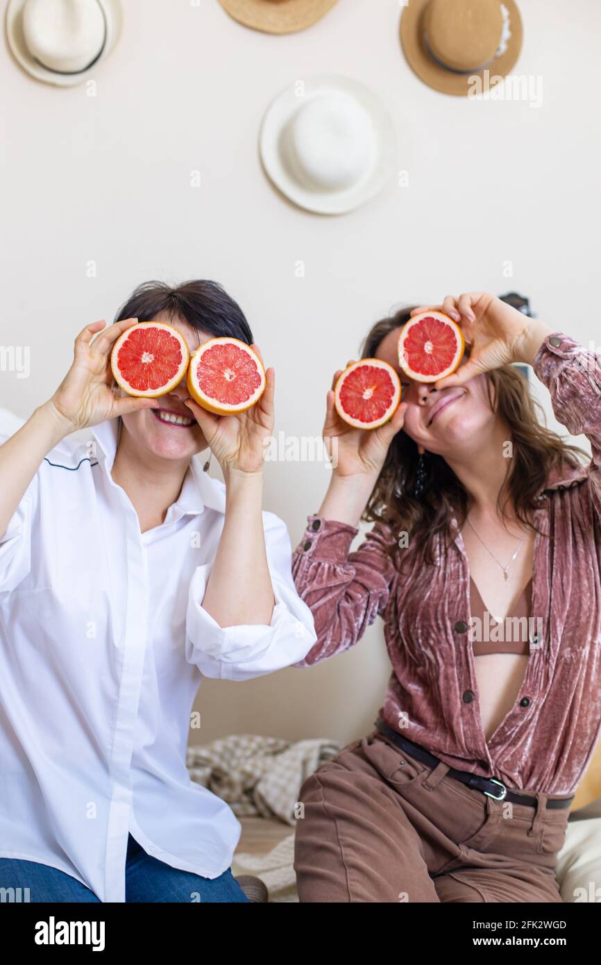 Felici le amiche che mostrano lingue che si posano con metà di pompelmo sugli occhi ridendo alla festa di gallina Foto Stock