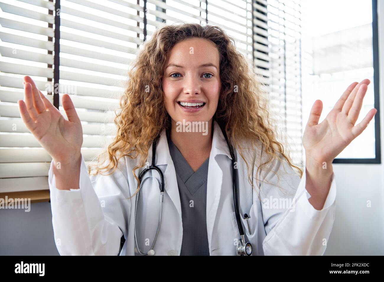 Felice giovane donna caucasica medico guardando la macchina fotografica e spiegando il paziente mentre fa la videochiamata in linea, concetti di servizio di consulazione medica domestica Foto Stock