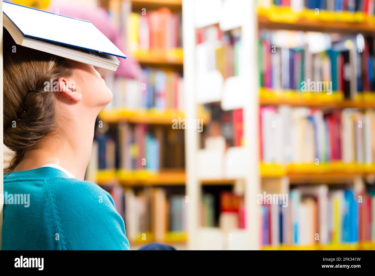 Studente - Giovane donna in libreria con il libro Imparare, lei è in stato di stop Foto Stock
