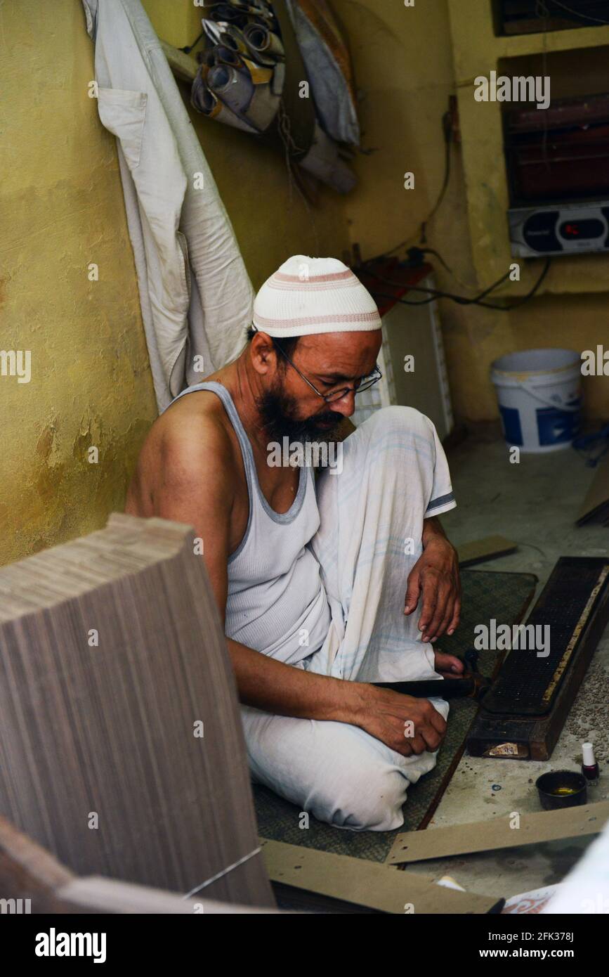 Un artigiano musulmano che lavora su un blocco di stampa per la saree indiane. Foto Stock