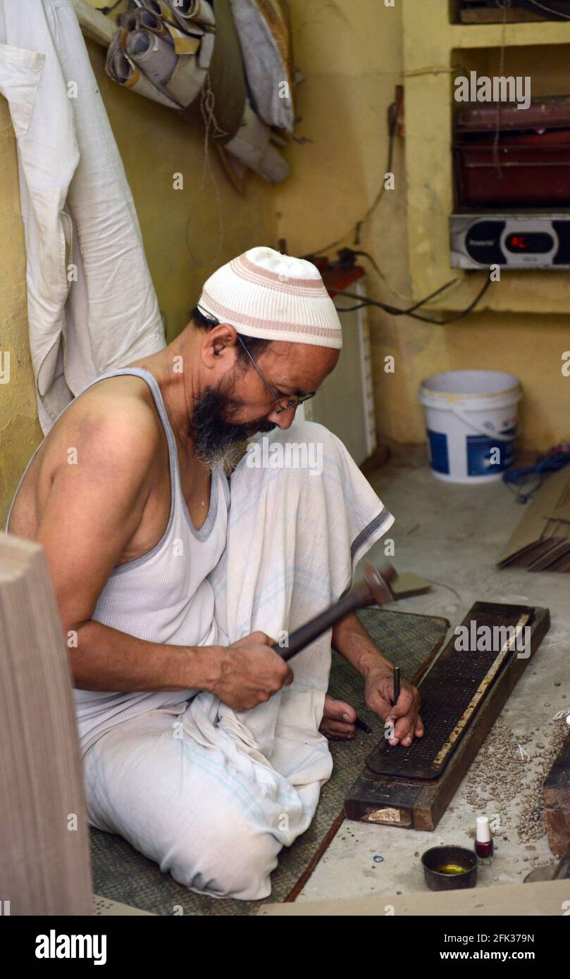 Un artigiano musulmano che lavora su un blocco di stampa per la saree indiane. Foto Stock