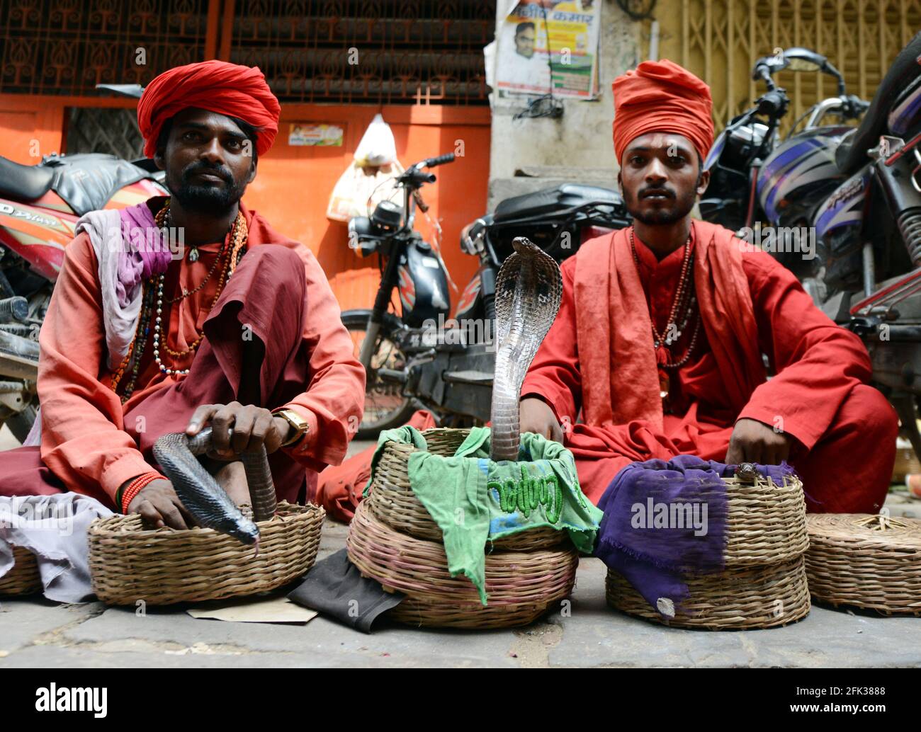 I tradizionali incantatori indiani di serpenti che intrattengono il cocciato nella città vecchia di Varanasi, India. Foto Stock
