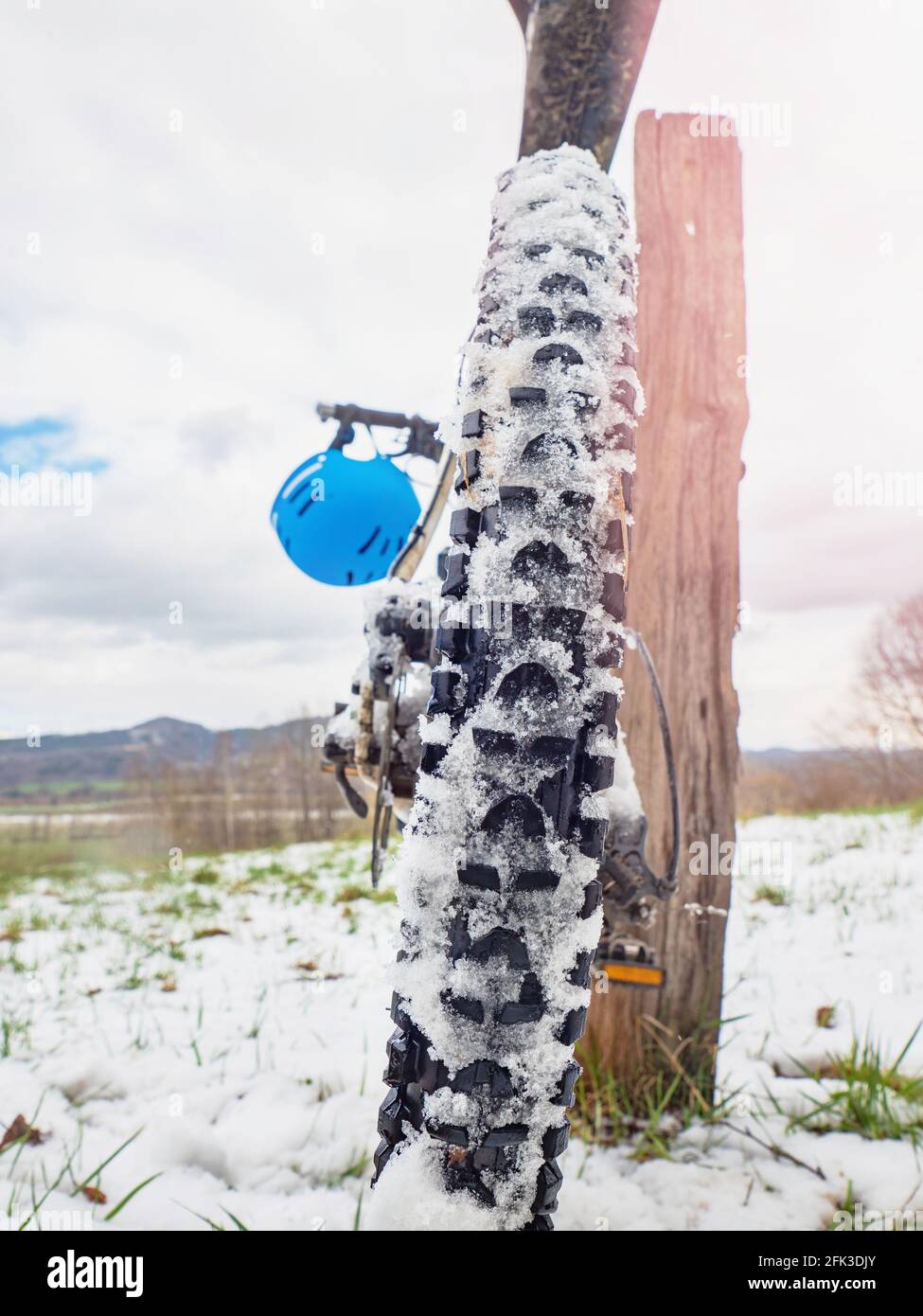 Ciclismo invernale. Dettaglio della ruota posteriore di montagna con neve tra le impugnature alte. Sport inverno sfondo. Foto Stock