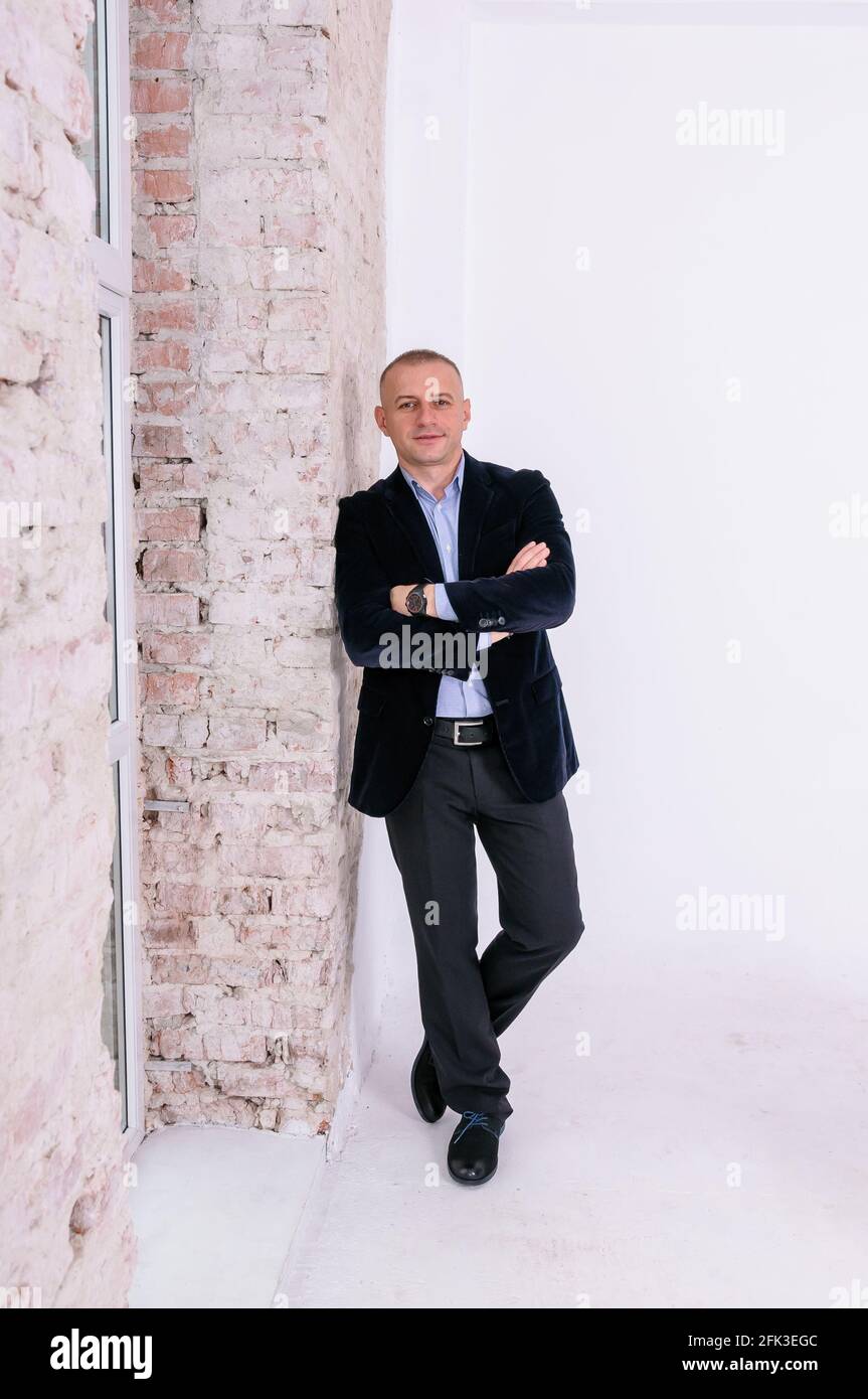 Uomo in camicia blu, pantaloni neri e giacca blu su fondo muro in mattoni  Foto stock - Alamy