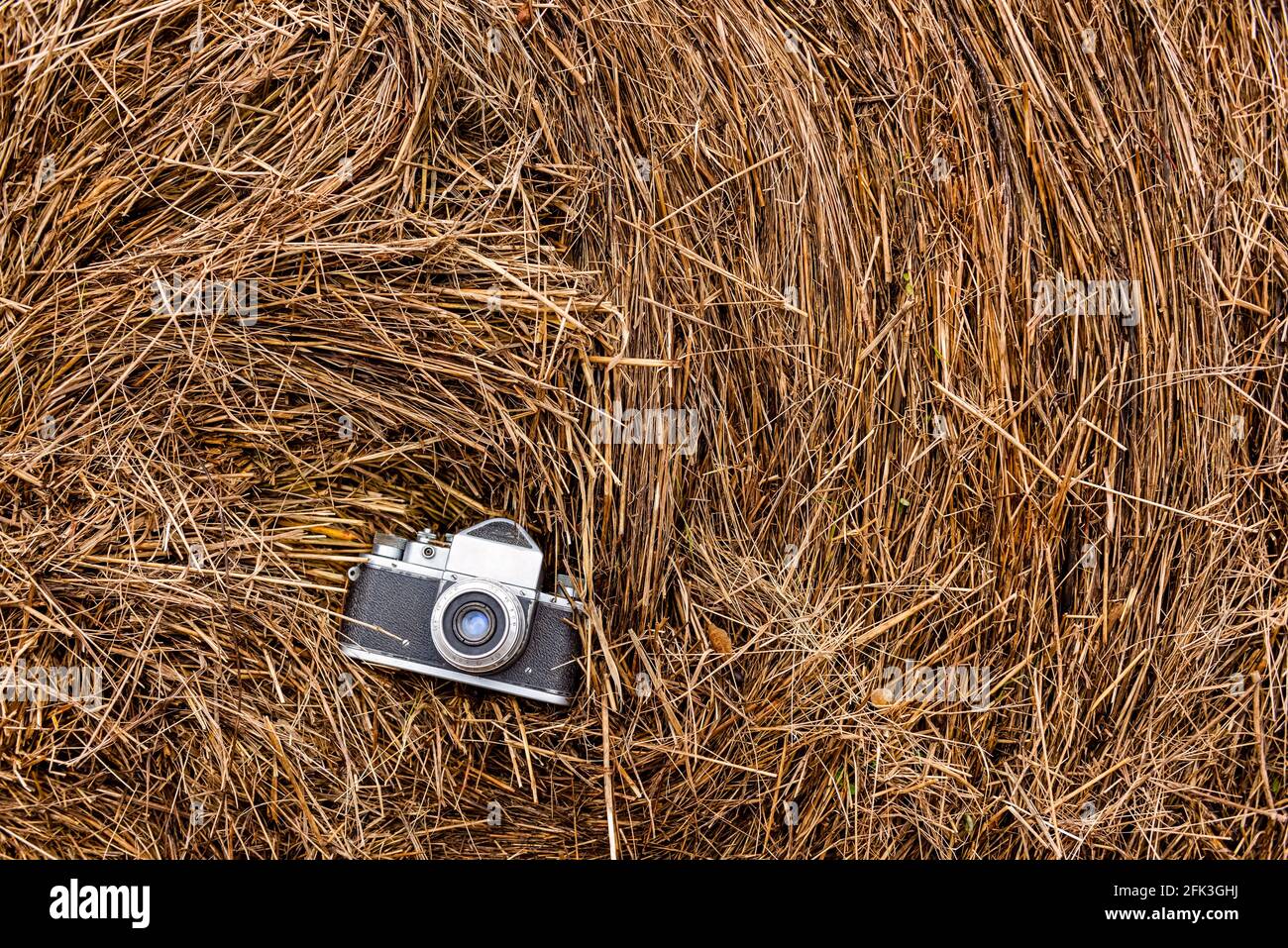 vecchia telecamera a film su una pila di fieno, sfondo naturale. foto orizzontale dall'alto Foto Stock