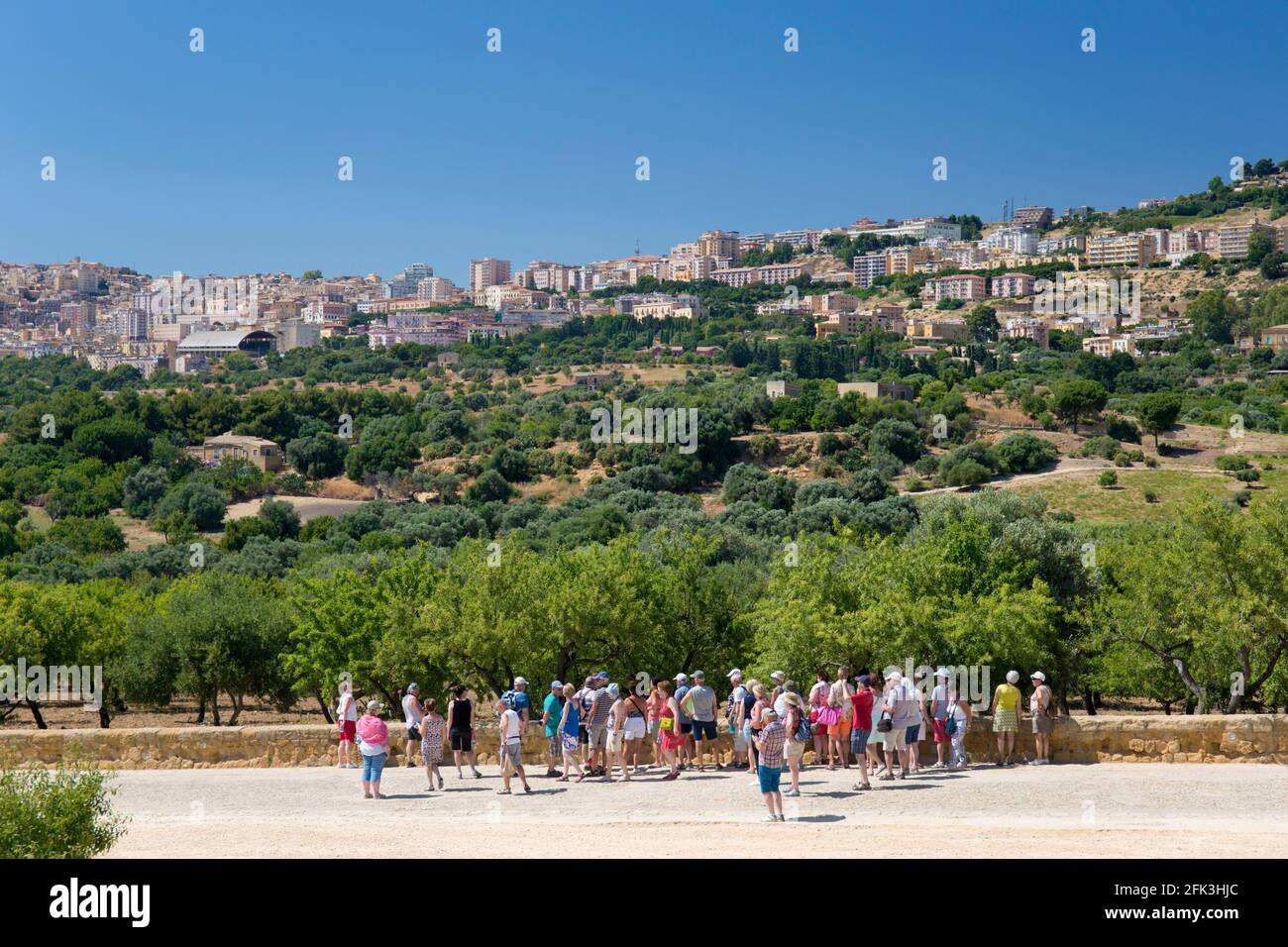Agrigento, Sicilia, Italia. Turisti sulla Via Sacra guardando verso la città attraverso il paesaggio di ulivi e mandorli, Valle dei Templi. Foto Stock
