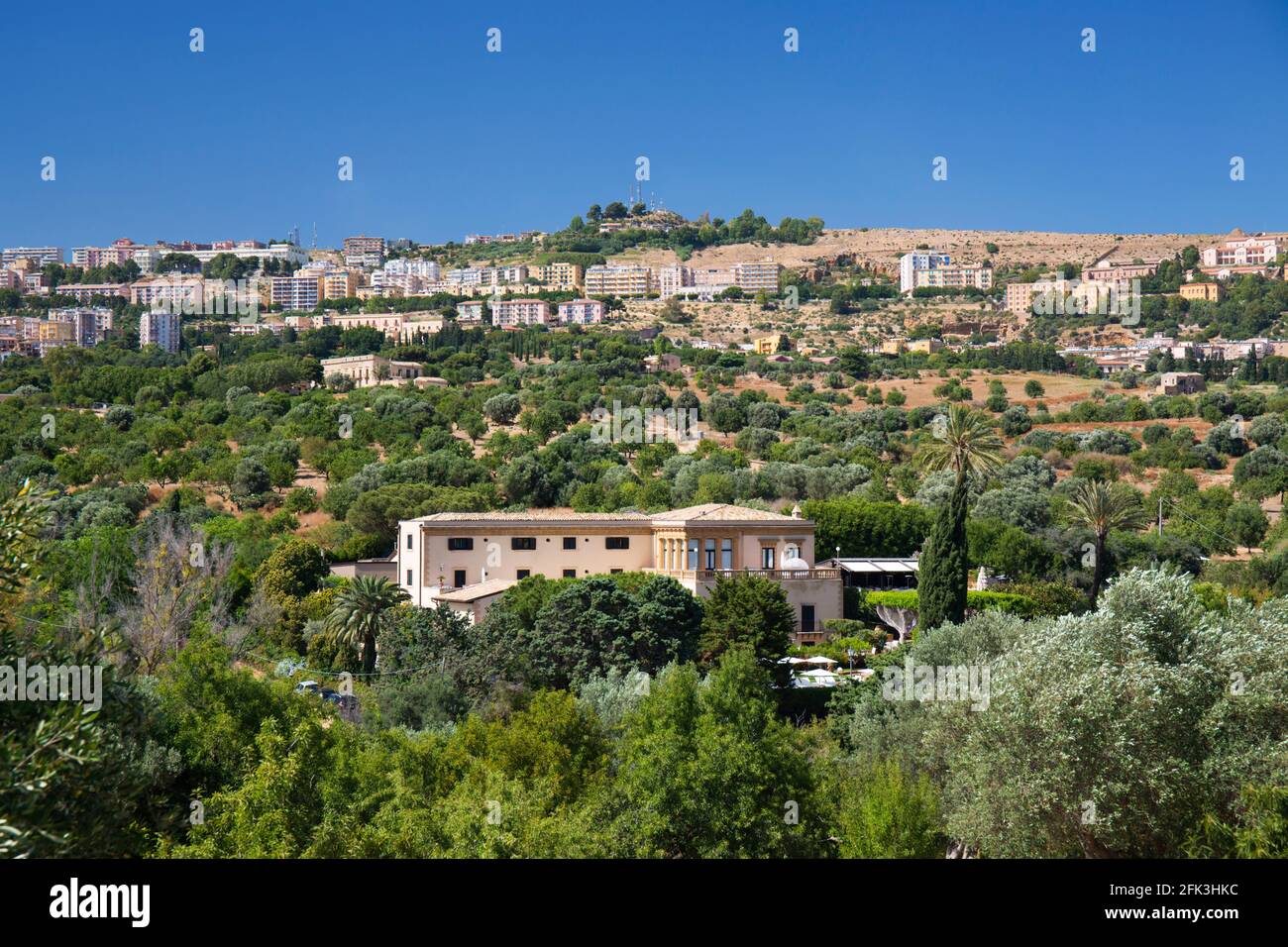 Agrigento, Sicilia, Italia. Vista sulla città attraverso il verde paesaggio di ulivi e mandorli, Valle dei Templi, Hotel Villa Athena prominente. Foto Stock