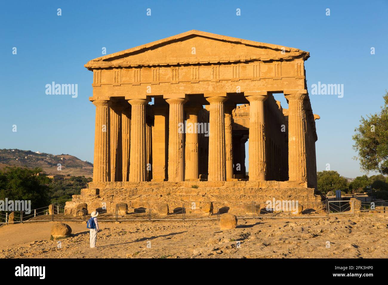 Agrigento, Sicilia, Italia. Fronte ovest del Tempio della Concordia illuminato dal sole tramontante, visitatore soleggiato che guarda in alto, Valle dei Templi. Foto Stock