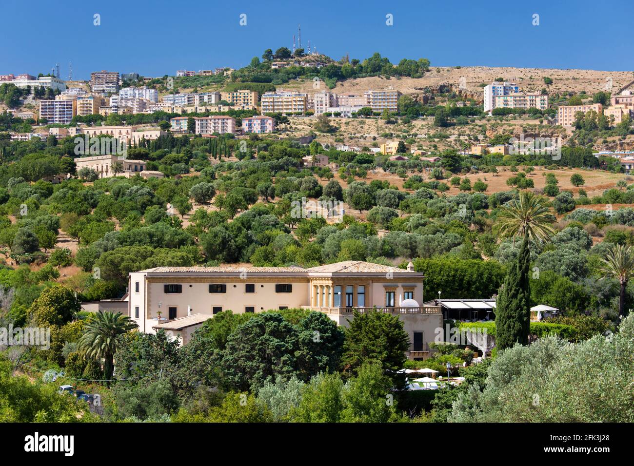 Agrigento, Sicilia, Italia. Vista sulla città attraverso il verde paesaggio di ulivi e mandorli, Valle dei Templi, Hotel Villa Athena prominente. Foto Stock