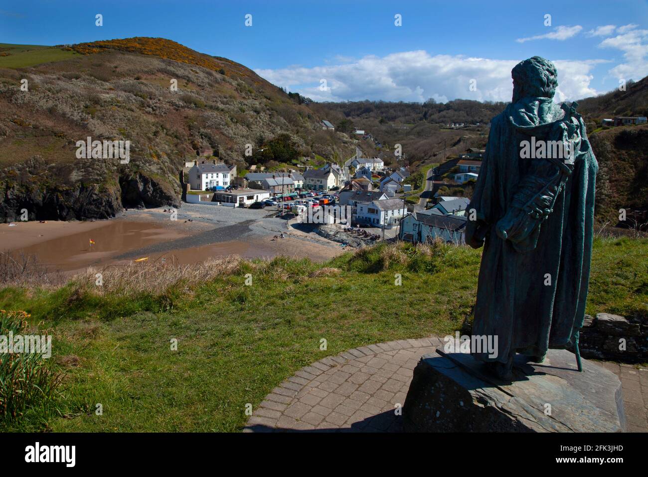 Llangrannog Beach a bassa marea e villaggio con la statua di Saint Crannog, Cardigan Bay, Cardigan, Galles, Regno Unito Foto Stock