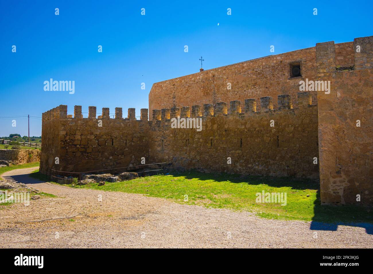 Muro del castello con fessure a freccia che protegge una semplice cattedrale quadrata con una croce su di esso Foto Stock