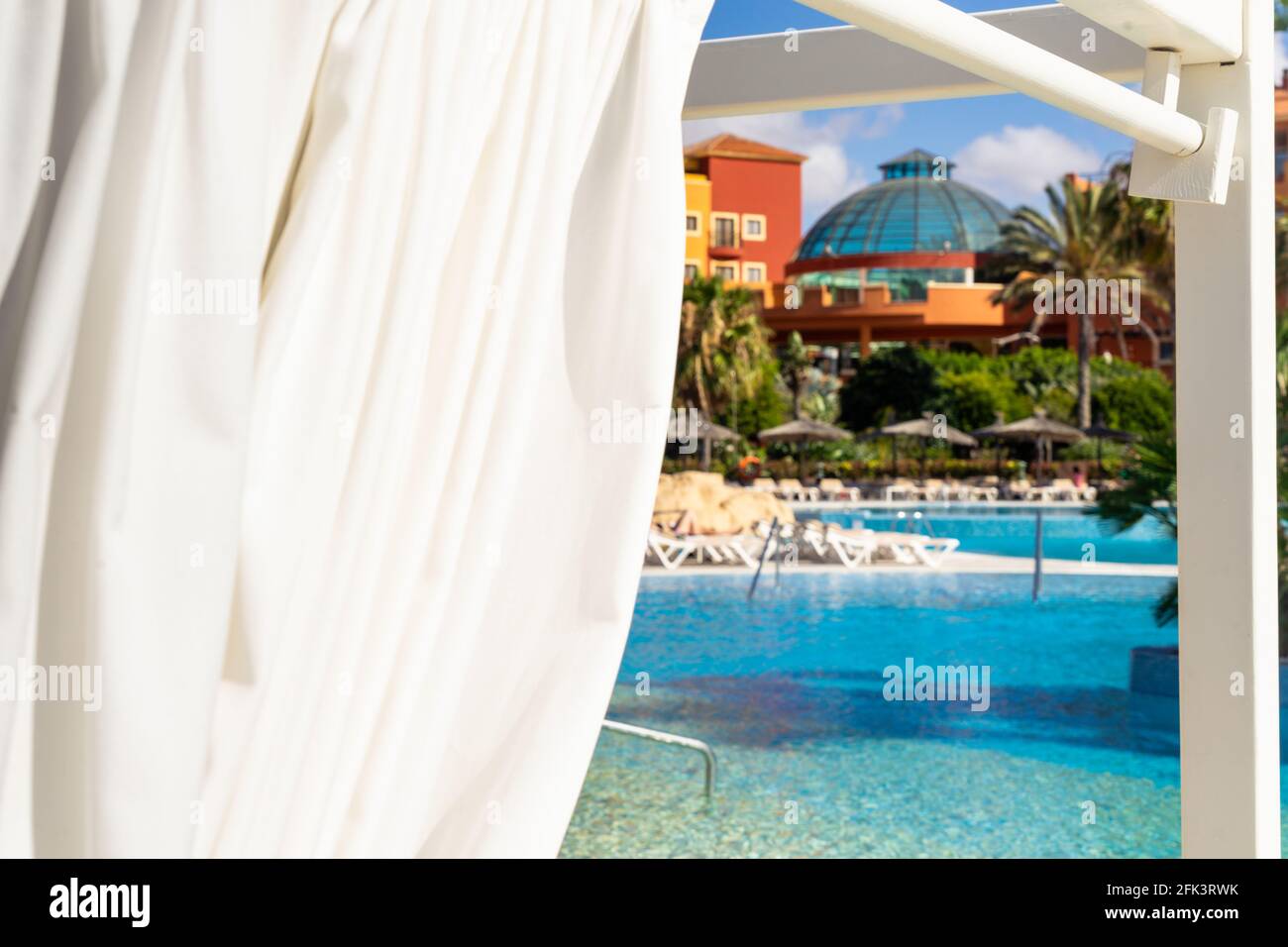 Guardando attraverso l'apertura in una tenda di sole al piscina di un hotel di lusso Foto Stock