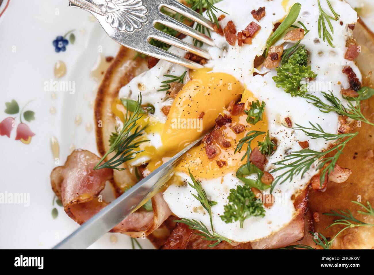 Vista dall'alto delle uova fritte con pancetta ed erbe. Processo di mangiare Foto Stock