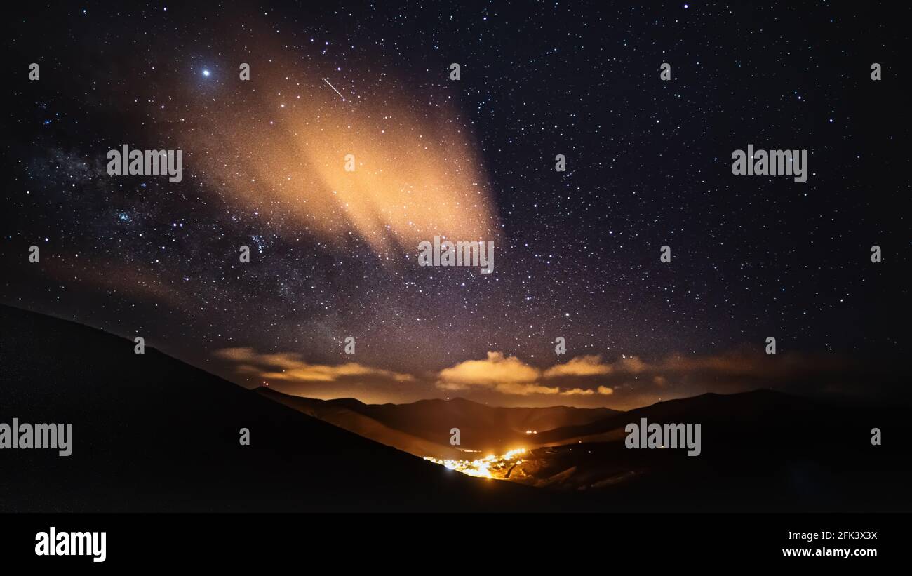 Fotografia notturna: Nuvole notturne illuminate e cielo stellato Foto Stock