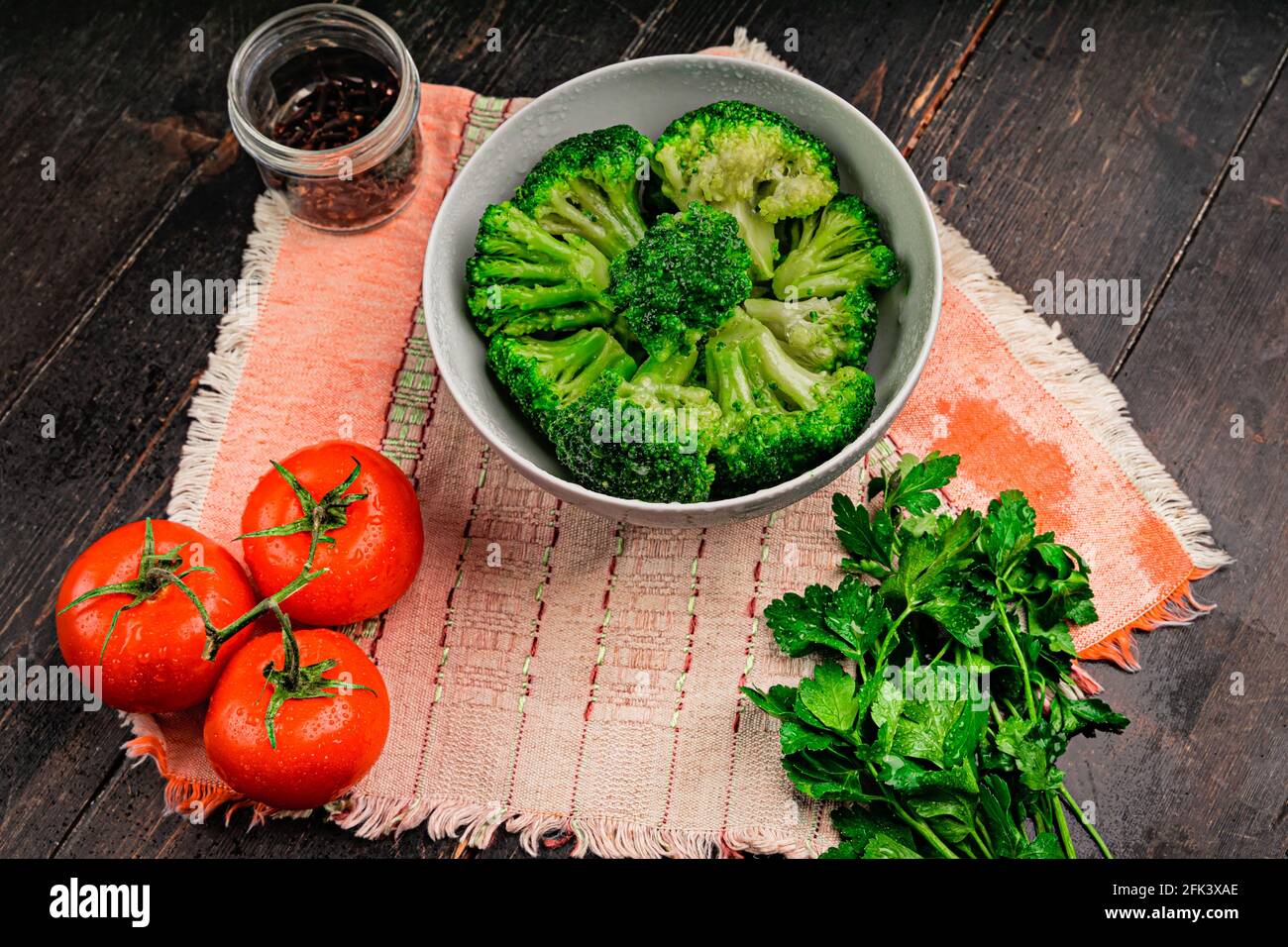 Mazzi di broccoli verdi pronti a cucinare. Broccoli in una piastra bianca su un tavolo di legno Foto Stock