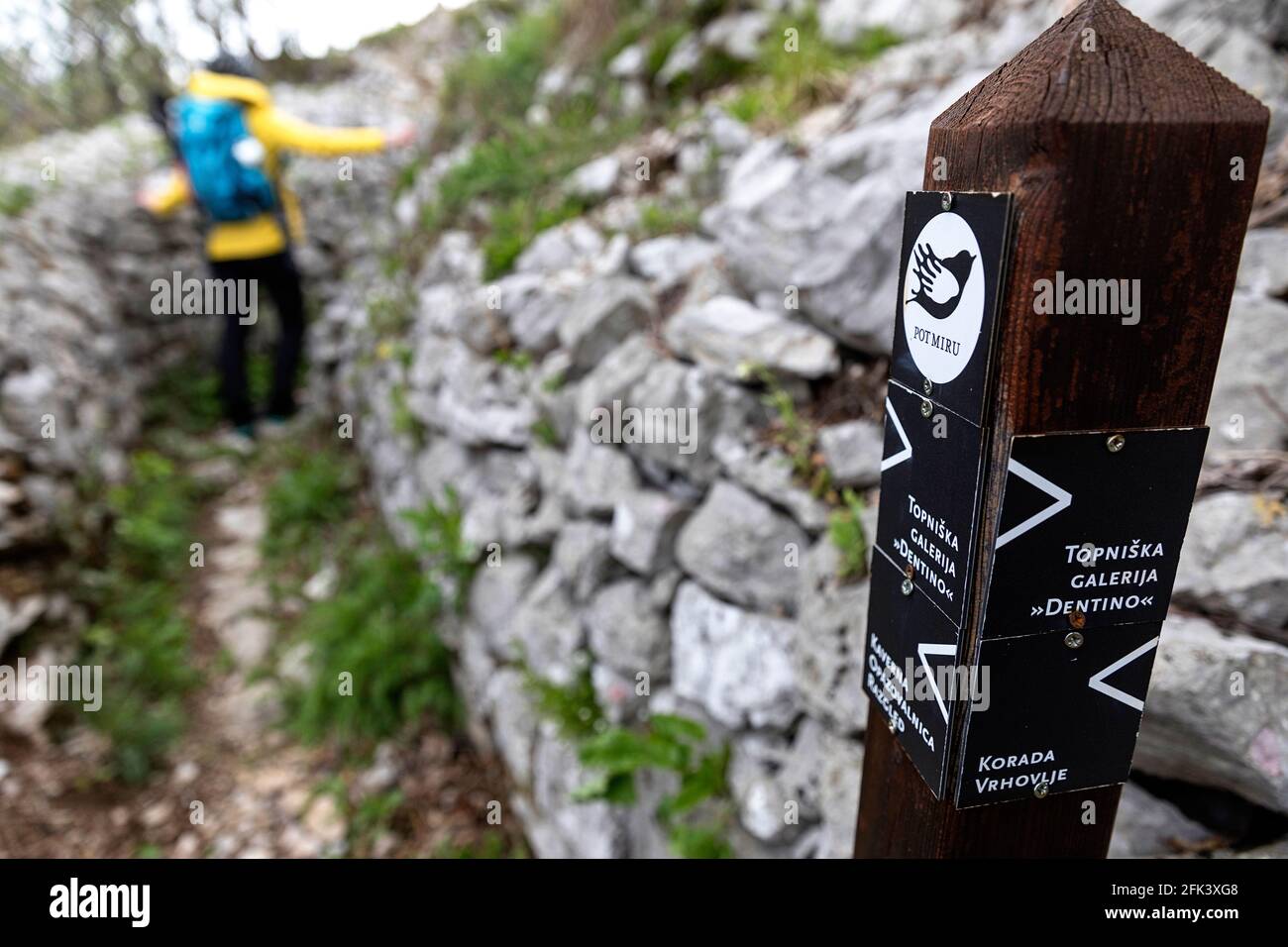 Signpost e una donna con uno zaino nel sistema di trincea della prima guerra mondiale a Sabotin, Slovenia Foto Stock