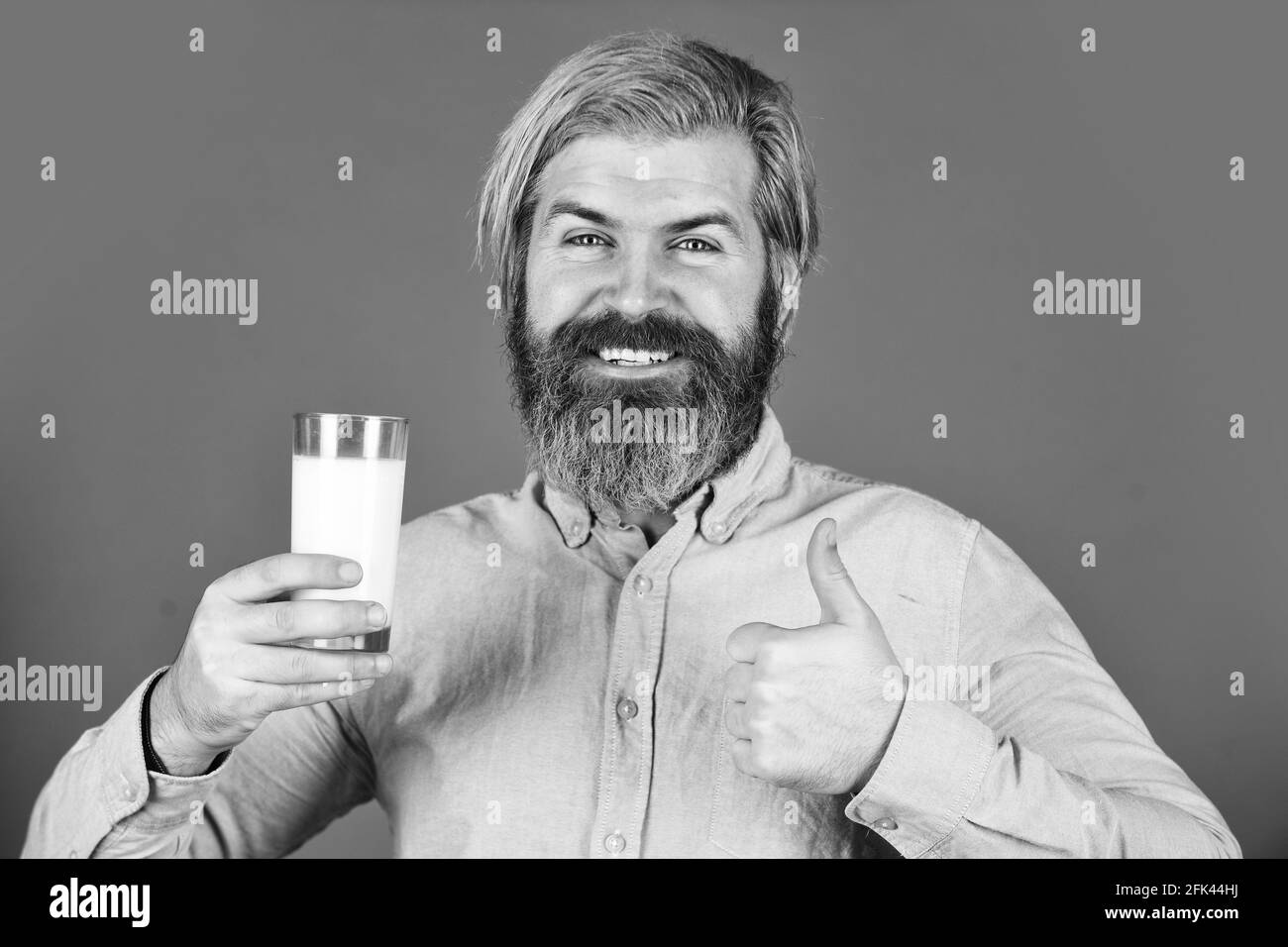 Concetto di latte vegano. L'uomo bearded tiene un bicchiere di latte. Latte pastorizzato. I lumi vegani sono costituiti da un'ampia varietà di fagioli, semi e grani. Bere proteine Foto Stock