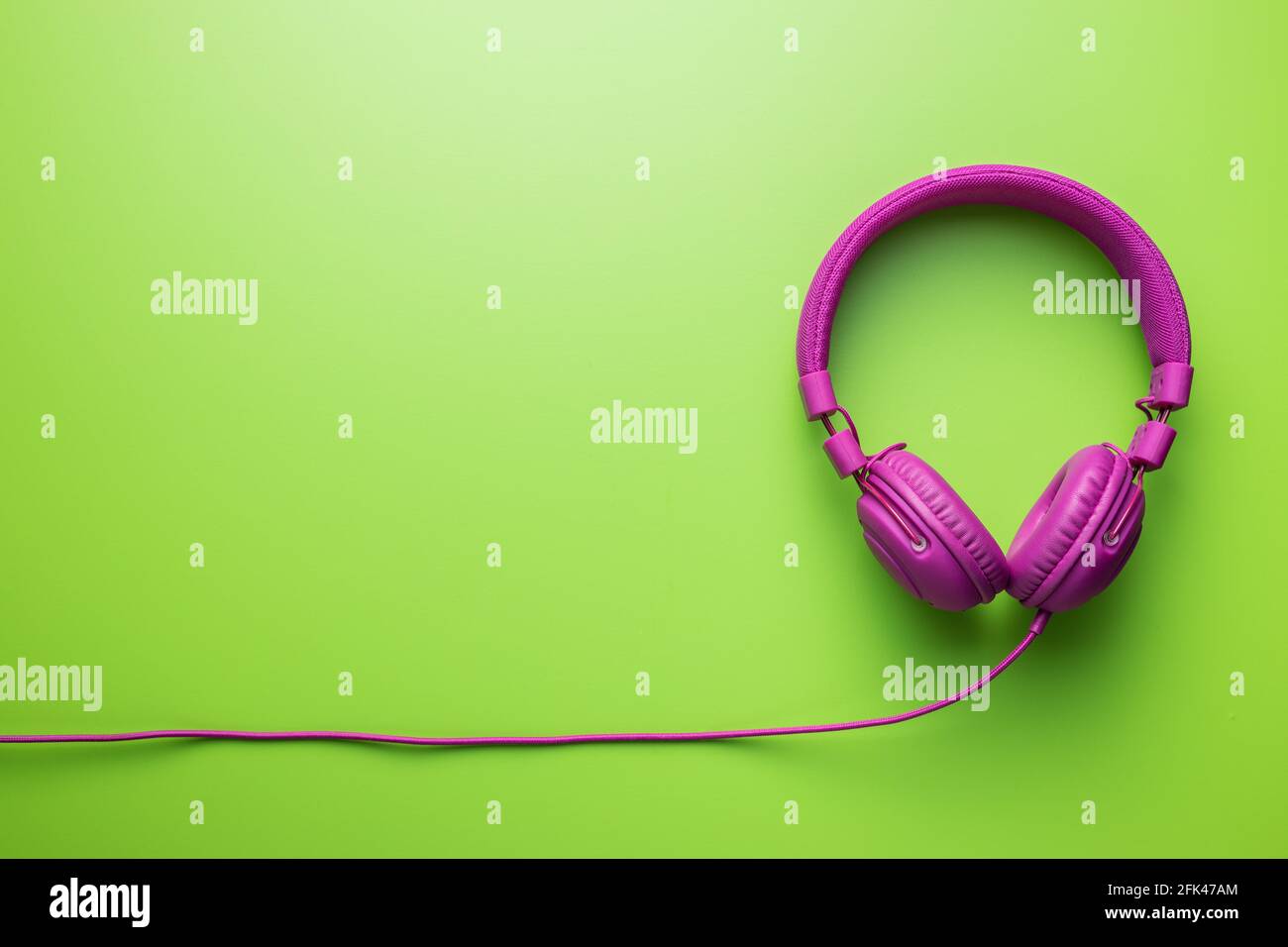 Cuffie stereo con fili rosa su sfondo verde. Vista dall'alto. Foto Stock