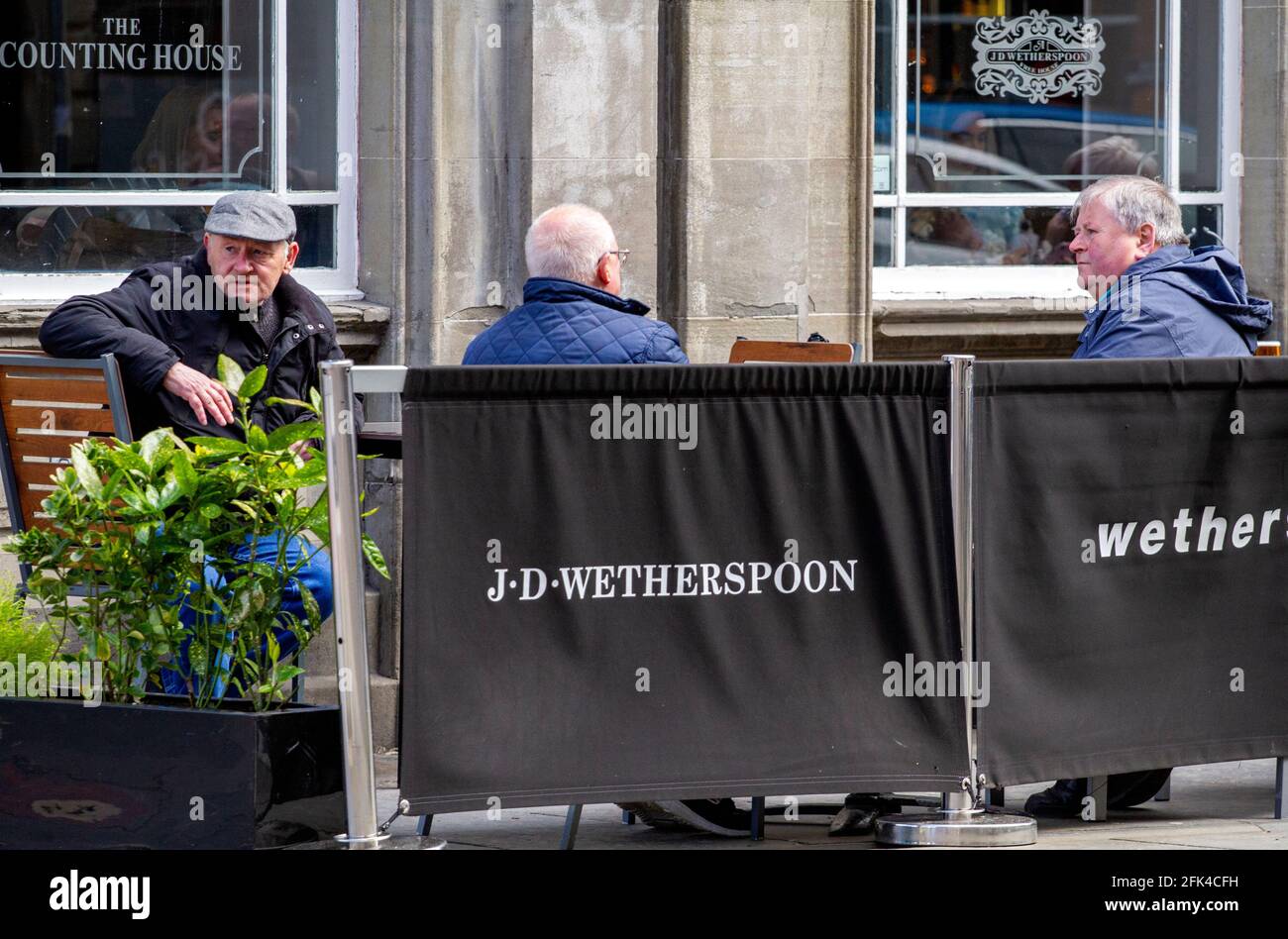 Dundee, Tayside, Scozia, Regno Unito. 28 aprile 2021. Regno Unito tempo: Freddo pomeriggio luminoso attraverso la Scozia nord-orientale con temperature che raggiungono i 9°C. I pub scozzesi hanno finalmente riaperto dopo mesi di rigide restrizioni di blocco del Covid-19. Il governo della Scozia ha permesso alle case pubbliche di tutto il paese di riaprire fino alle 22:00, purché abbiano giardini di birreria all'aperto. I residenti locali approfittano delle nuove norme di blocco e delle condizioni meteorologiche favorevoli per incontrare il pub Wetherspoon`s Counting House per gustare un drink nel centro di Dundee. Credit: Dundee Photographics/Alamy Live Foto Stock