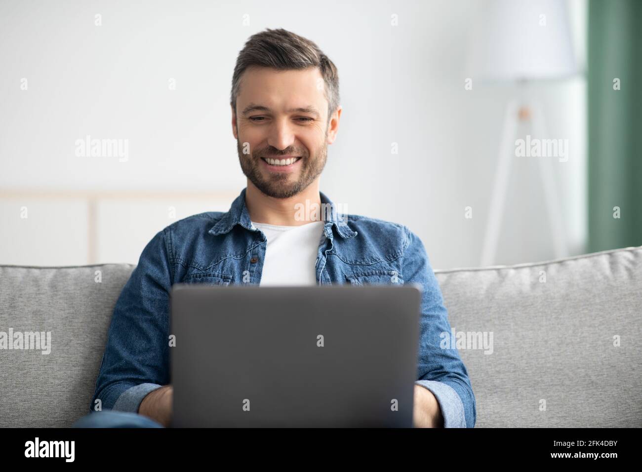 Closeup di un uomo con un portatore positivo che utilizza un computer portatile a casa Foto Stock