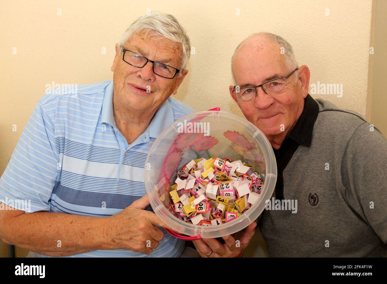 Dundonald , Ayrshire, Scozia. Due uomini anziani con secchio di biglietti di lotteria come raccogliere soldi per la carità in un complesso residenziale protetto Foto Stock