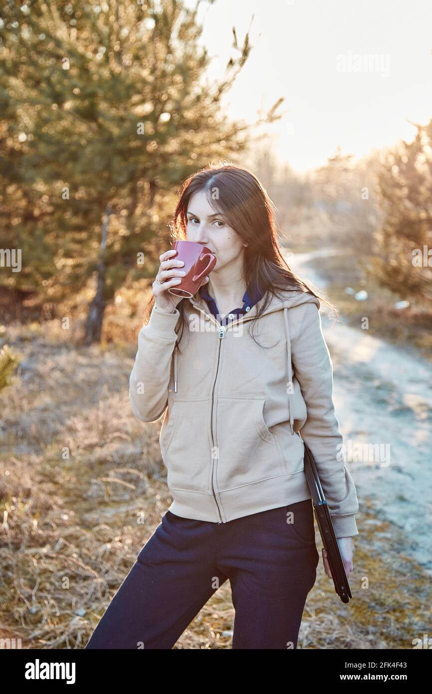 Giovane donna con taccuino e tazza di tè nella foresta. Solitudine e aspetti negativi del concetto freelance. Concetto di stress emotivo. Foto di alta qualità Foto Stock