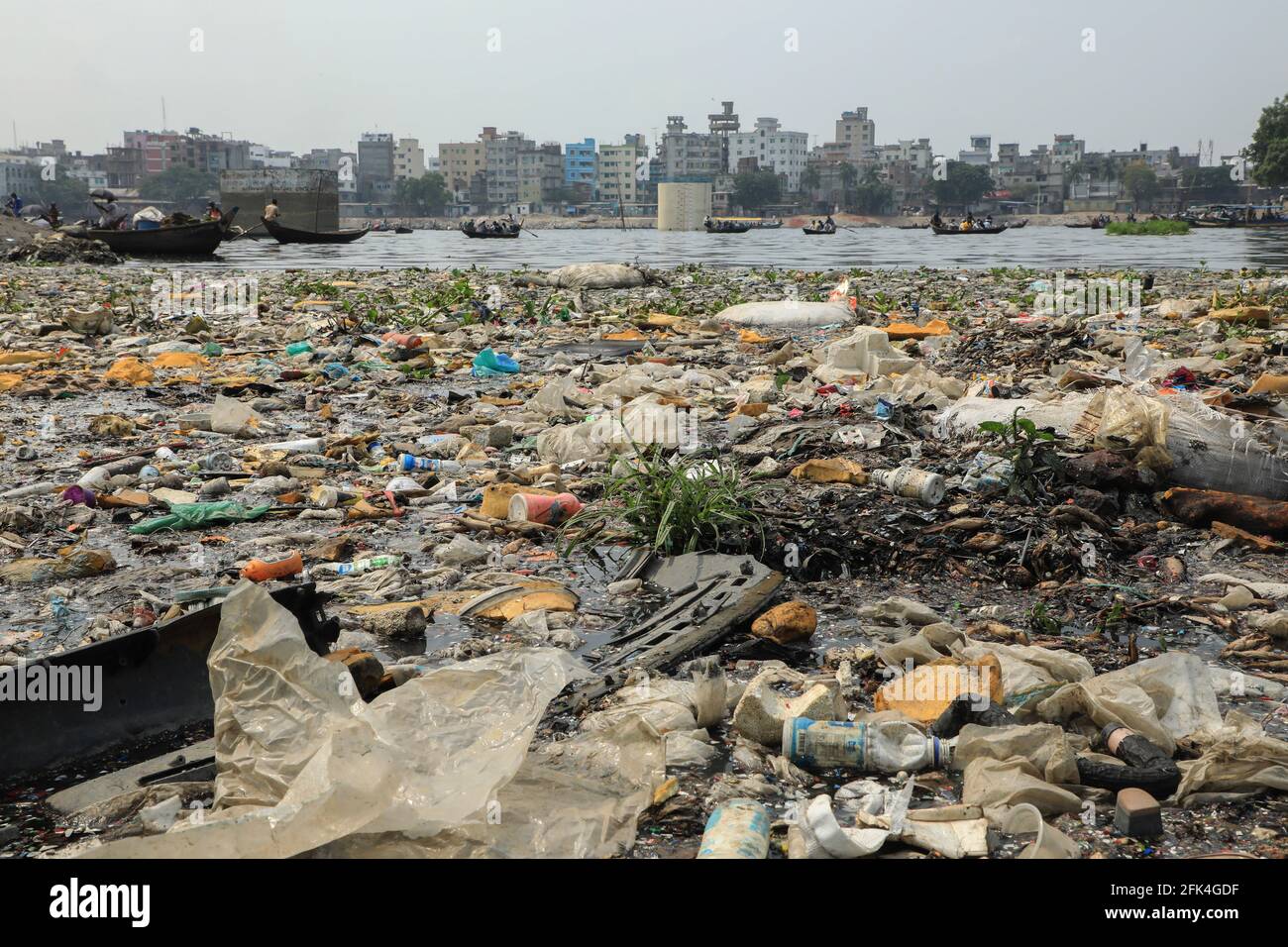 Dhaka, Bangladesh. 28 Apr 2021. Rifiuti di plastica sulle rive come la gente attraversa in barca sopra il campo acqua nera del fiume Buriganga in Dhaka. Milioni di metri cubi di rifiuti tossici provenienti dalle concerie e migliaia di altre industrie, con un enorme volume di acque reflue non trattate provenienti dalla città di Dhaka, hanno causato l'inquinamento idrico nei fiumi per raggiungere livelli allarmanti. Credit: SOPA Images Limited/Alamy Live News Foto Stock