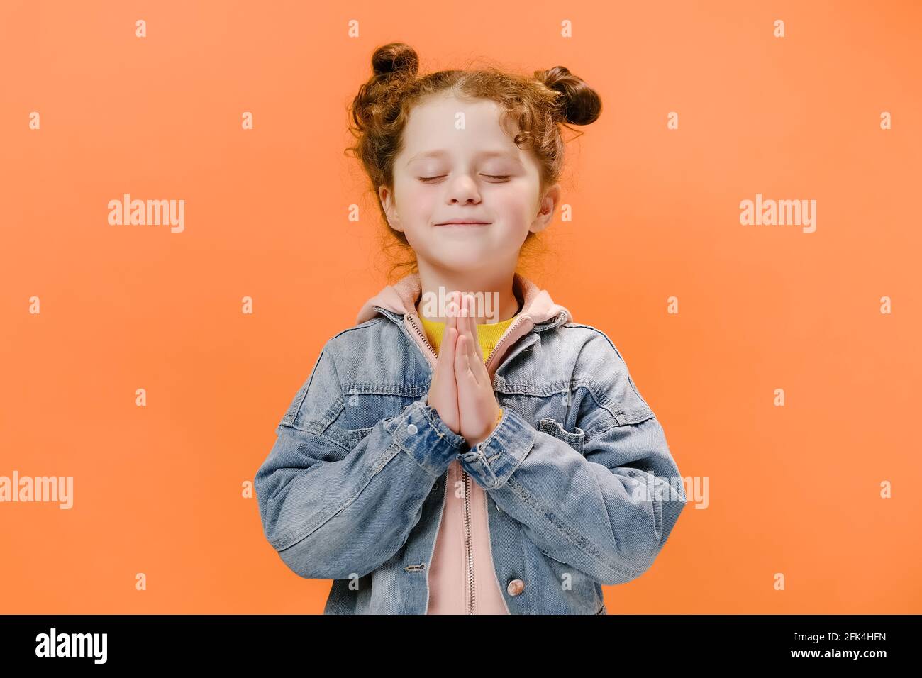 Ritratto di carino ragazzino caucasico che prega con gli occhi chiusi, le mani piegate nel concetto di preghiera per la fede, la spiritualità e la religione Foto Stock