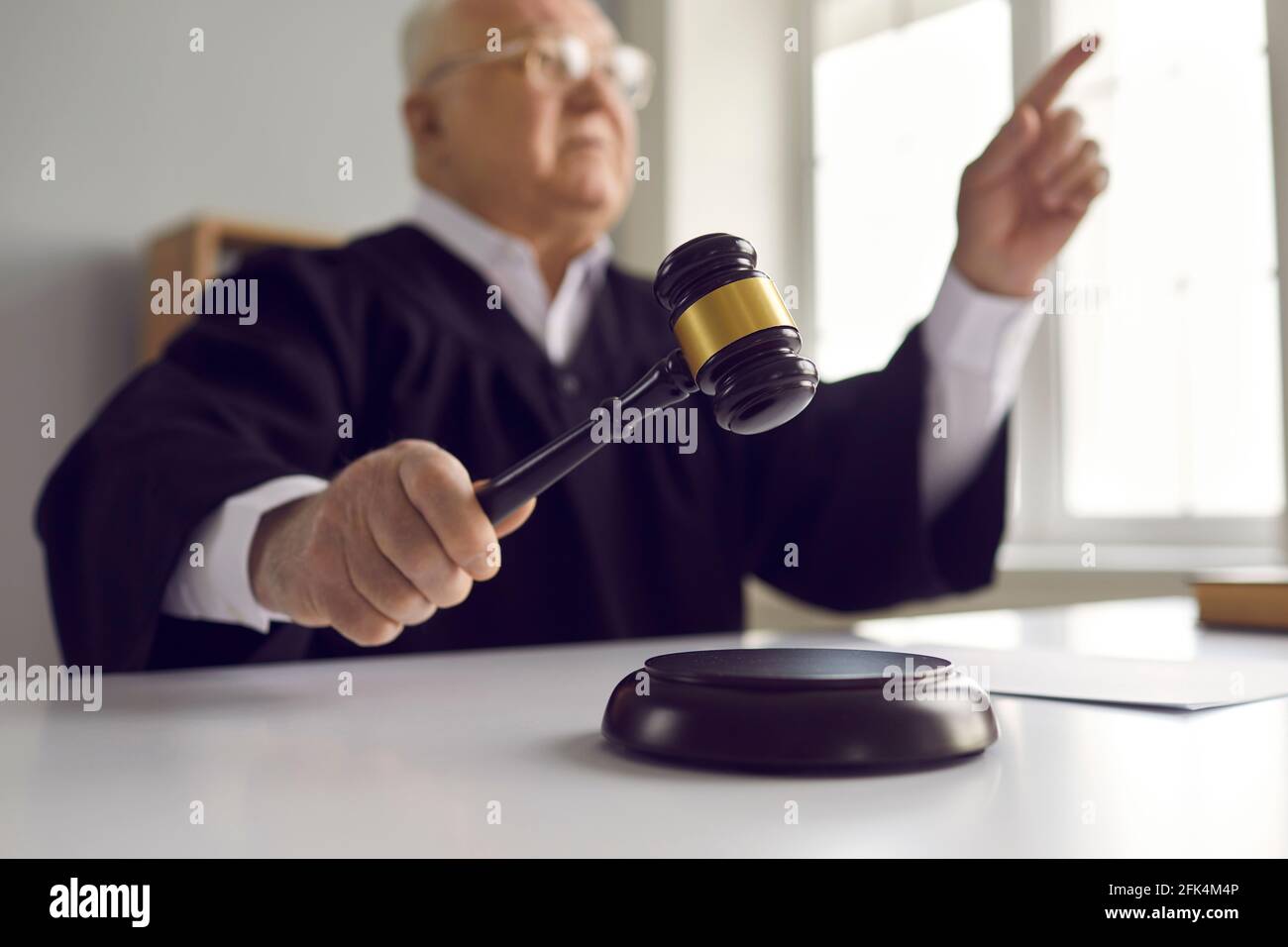 Primo piano della mano di un giudice maturo che colpisce il blocco sonoro in legno con gavel in tribunale Foto Stock