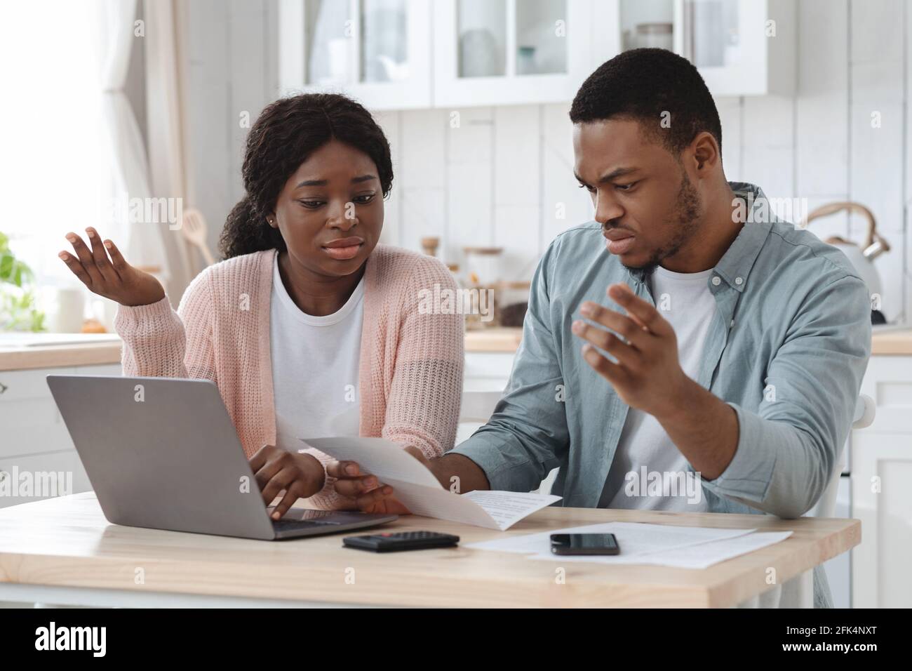 Problemi di assicurazione della famiglia. Ritratto di una coppia nera frustrato che verifica i documenti a casa Foto Stock