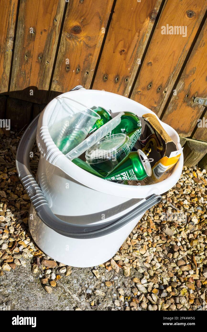 Un secchio contenente carta, cartone, plastica dura e lattine in viaggio verso il contenitore di riciclaggio Foto Stock